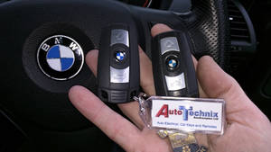 手在方向盤附近拿著帶有Auto Technix鎖匙扣的BMW車匙。 — 汽車 壁紙