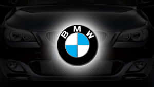 深色引擎蓋上發光的BMW標誌，車頭燈可見。
