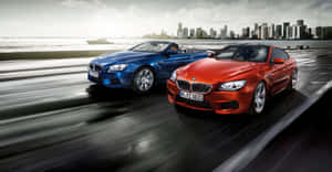 日落時分，兩輛BMW跑車在靠近城市天際線的海岸公路上疾馳。