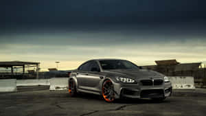 銀色BMW M6配橙色輪圈，在黃昏時停泊在工業用地。