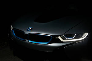 黑色BMW i8在黑暗中帶有發光藍色飾條和頭燈的特寫。