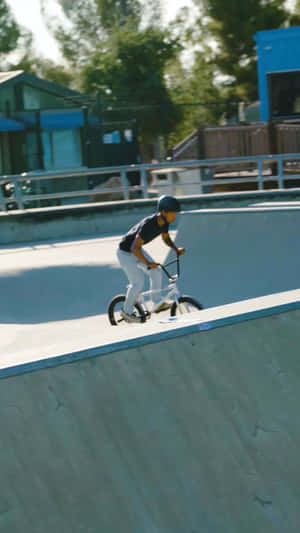 年輕BMX車手在混凝土滑板坡道上表演轉彎。