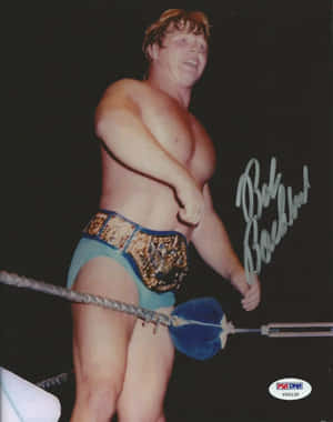 摔角手 Bob Backlund 在擂台上手持藍色狼牙棒和冠軍腰帶的簽名照片。