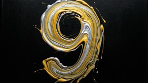 金色和銀色顏料在黑色背景上旋轉形成數字九的抽象漩渦。