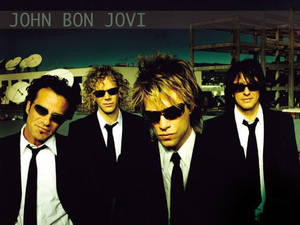 John Bon Jovi 和樂團成員在黃昏時穿著黑色西裝和太陽眼鏡。