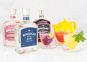 三個Boodles氈酒瓶和色彩繽紛的雞尾酒在白色表面上。 — 明亮 壁紙