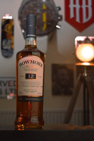 一瓶 Bowmore 12 年威士忌放在酒吧上，帶有溫暖的燈光和裝飾。