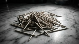 一堆木製牙籤在雲石表面上，帶有戲劇性的燈光。