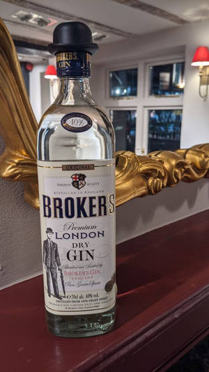 Brokers Gin 瓶戴高帽在紅色表面上，旁邊有金色鏡子在酒吧。
