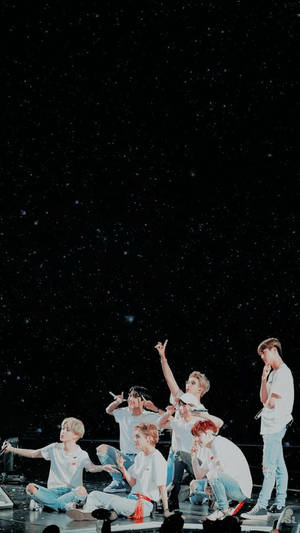 K-pop 組合在星空背景的舞台上表演。