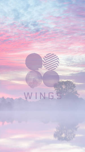 粉紅色和藍色的天空倒映在霧氣瀰漫的水面上，帶有樹木和「WINGS」標誌。