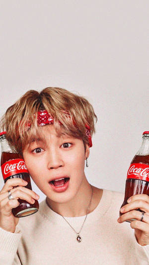 戴頭巾的年輕男子，面帶愉快表情拿著兩瓶可口可樂。 — Jimin GIF 壁紙