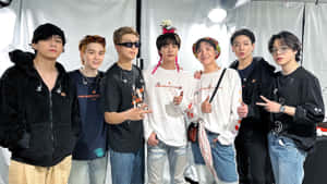 七位K-pop偶像穿著休閒街頭服飾在攝影棚中一起擺姿勢。