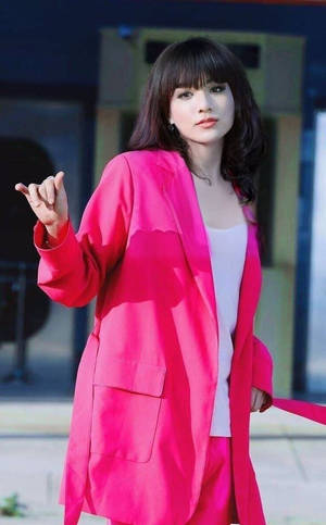 身穿粉紅色西裝外套的女性在戶外做出手勢