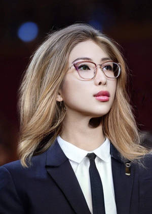 穿著商務服裝的女性，戴眼鏡和粉色唇膏，向上看。