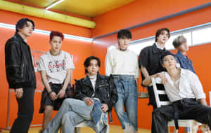 七位時尚的K-pop男孩在光線明亮的橙色工作室中擺姿勢。