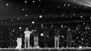 七位表演者在舞台上，夜間音樂會期間雪花飄落。