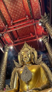 金色佛像在寺廟中，紅色天花板和飄散的香煙