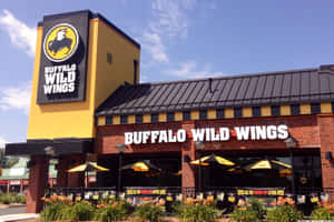 Buffalo Wild Wings餐廳，黃色招牌，黃色太陽傘下設有戶外座位。