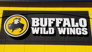 黃黑牆上帶有黑色水牛吉祥物的 Buffalo Wild Wings 餐廳招牌。