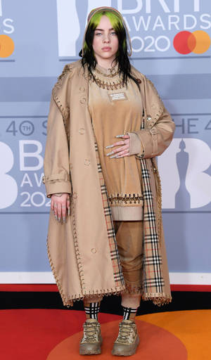 Billie Eilish 在2020年全英音樂獎紅地毯上身穿米色風衣和靴子。