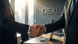 兩名西裝男子在帶有「DEAL」標誌的辦公室握手。