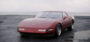 紅色Corvette跑車停泊在海洋附近的濕瀝青上，天空灰暗。