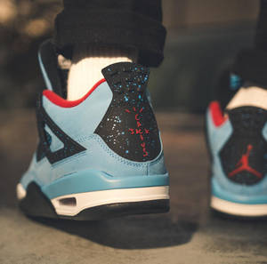 淺藍、黑色和紅色 Air Jordan 4 運動鞋，鞋跟帶有塗鴉。