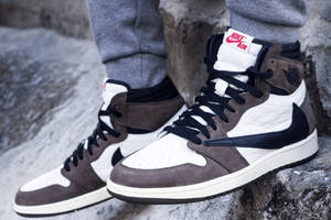 身穿灰色運動褲和Nike Air Jordan運動鞋的人站在岩石地形上。