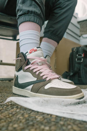 灰色同白色Nike Air波鞋嘅特寫，粉紅色鞋帶，喺碎石上。