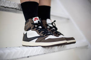 棕色、黑色和白色的 Nike Air Jordan 運動鞋放在白色樓梯上，搭配黑色襪子。