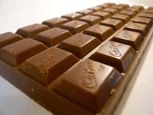一條 Cadbury 朱古力條，每個獨立方塊上都壓印咗品牌名稱。 — 4:3 壁紙