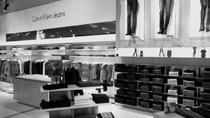 Calvin Klein Jeans 店舖的黑白室內設計，服裝架和玻璃陳列櫃中的人體模型腿部。