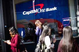 人們在夜晚走過一間Capital One Bank，帶有發光的標牌。