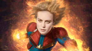 Captain Marvel 在熾熱的太空中飛翔，拳頭發光，表情堅定。 — 地球超人 壁紙