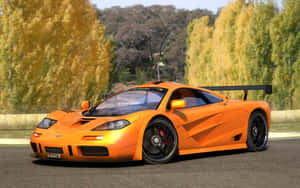 橙色McLaren F1跑車在道路上，背景有秋樹。 — Steam Deck OLED 壁紙