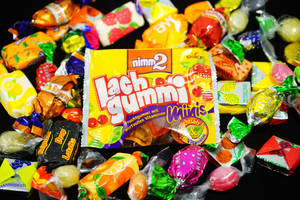 黑色表面上色彩繽紛的包裝糖果和Lachgummi Minis包裝。