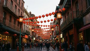 一條熱鬧的街道，紅色燈籠懸掛在建築物之間，人們在下面行走。