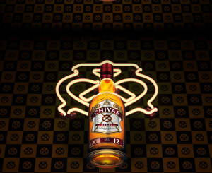 Chivas Regal威士忌酒瓶在格仔背景上被霓虹燈牌照亮。