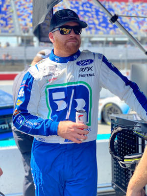 身穿賽車服的NASCAR車手在賽道上拿著一個罐子。