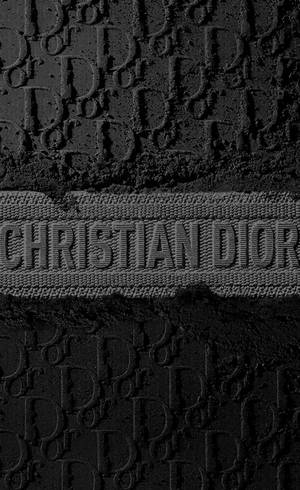 壓花 Christian Dior 標誌圖案在紋理黑色布料上的特寫。