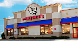 陽光普照的天空下，Chuck E Cheese's 餐廳配有吉祥物和藍色遮陽篷。