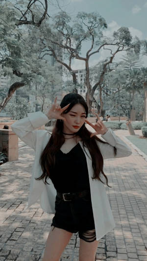 年輕女性在公園裡穿著白色西裝外套和黑色短褲，擺出手指槍的姿勢。