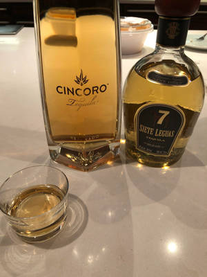 白色檯面上的兩瓶龍舌蘭酒和一個玻璃杯。