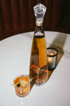 Cincoro龍舌蘭酒瓶和雞尾酒杯，白色桌子上有蠟燭