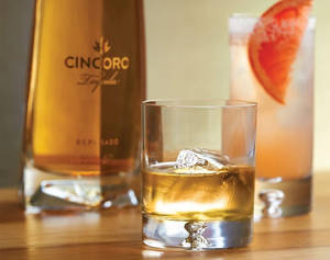 Cincoro龍舌蘭酒瓶同木枱上嘅兩杯雞尾酒。