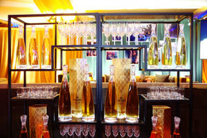 豪華酒吧展示，金色Cincoro酒瓶和水晶杯在溫暖燈光下。