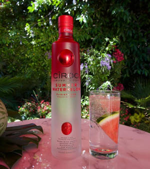 花園粉紅色大理石桌上的紅色Ciroc西瓜伏特加酒瓶和西瓜飲料。