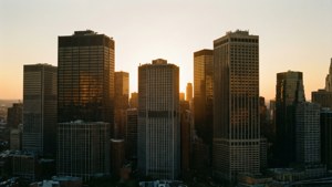 金色夕陽照亮密集市中心天際線中的高聳玻璃摩天大樓。