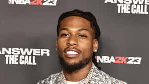 留著辮子和鬍鬚的男子在NBA 2K23活動中微笑。